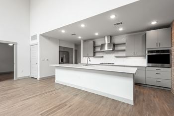 a kitchen with a large white island with a sink and a stove